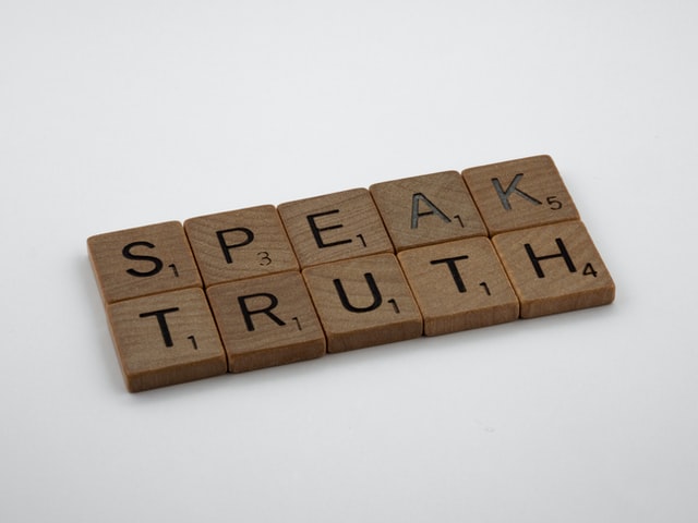 brown wooden blocks spelling "speak truth" on a white table